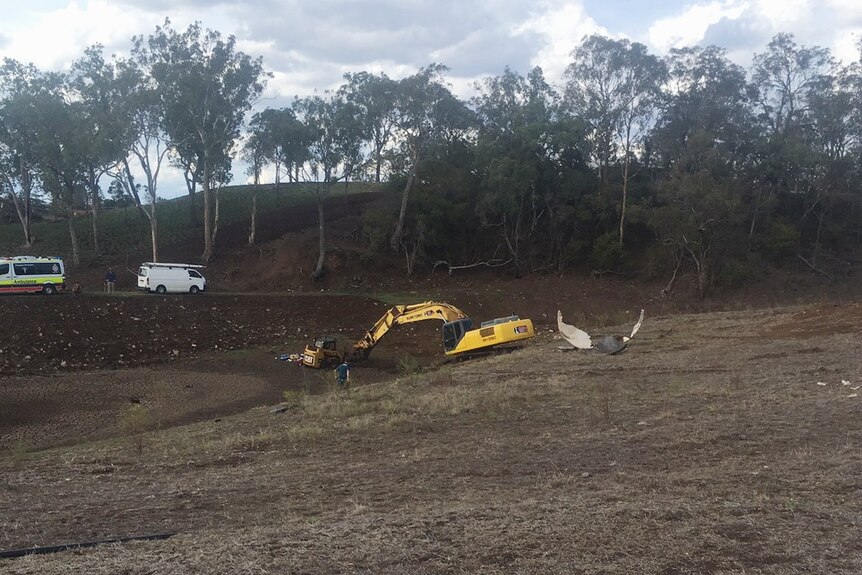An excavator at a Toowoomba property near a dam.