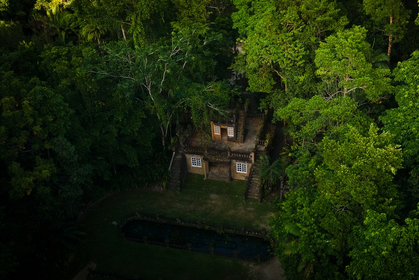 A drone shot of a castle inside a rainforest.