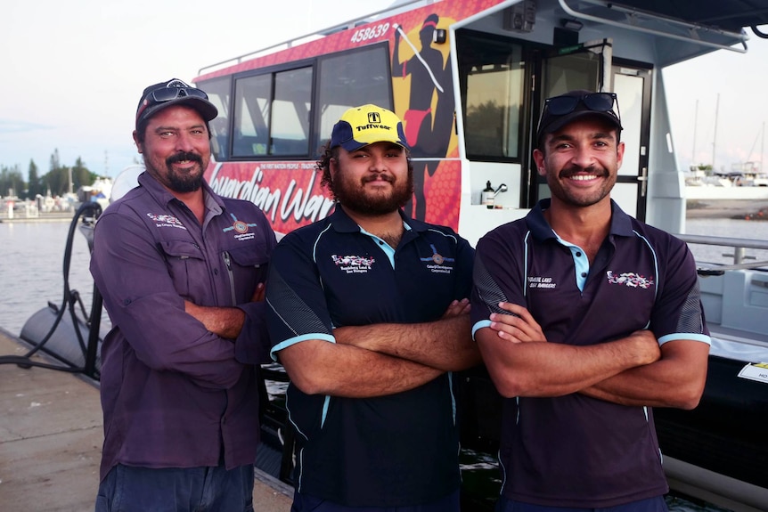 Jacob Bulow, Kailu Craigie and Isaiah McGarrow stand with their arms crossed, in front of their patrol boat