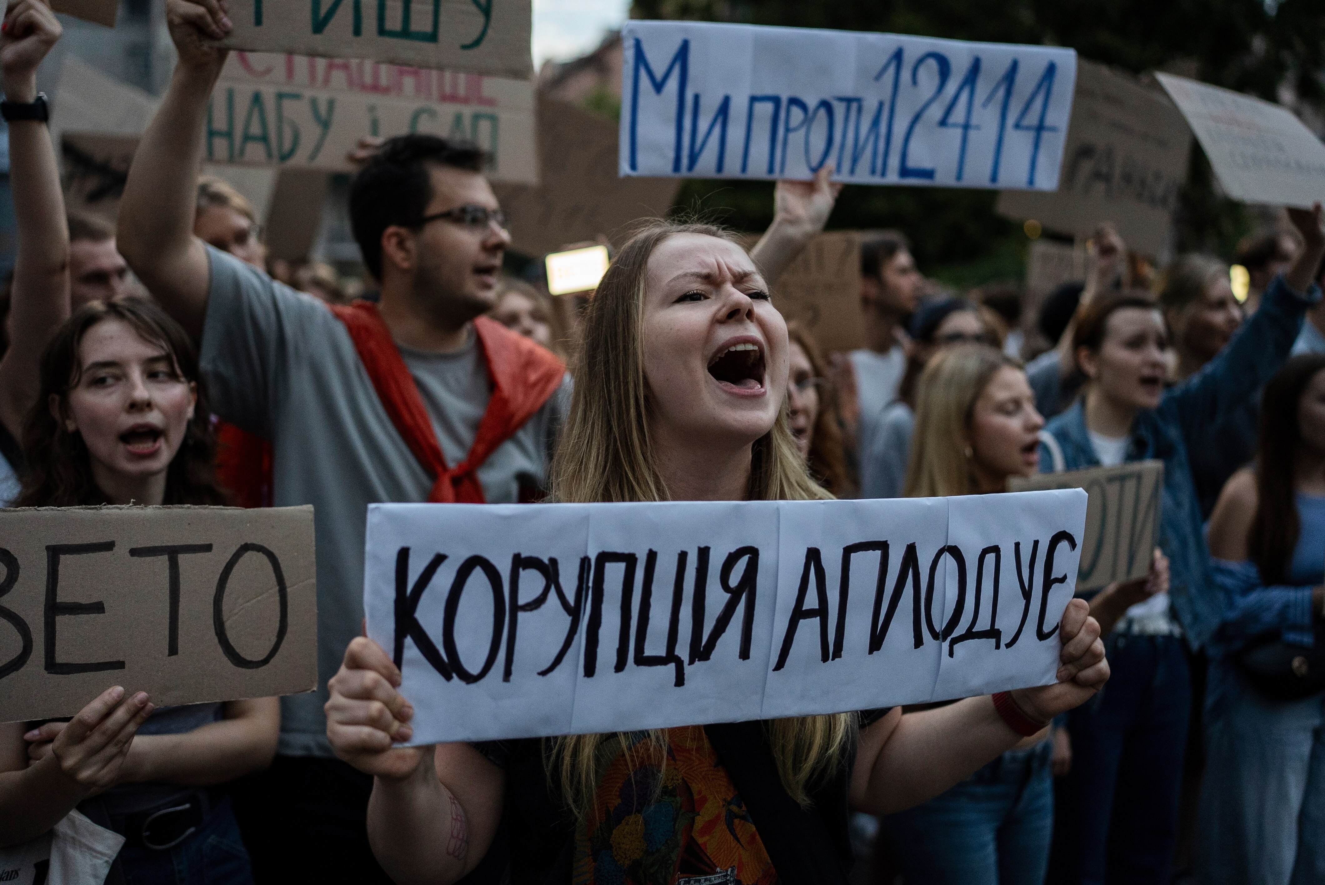 Young woman in the middle of a protest holding up a sign and shouting.