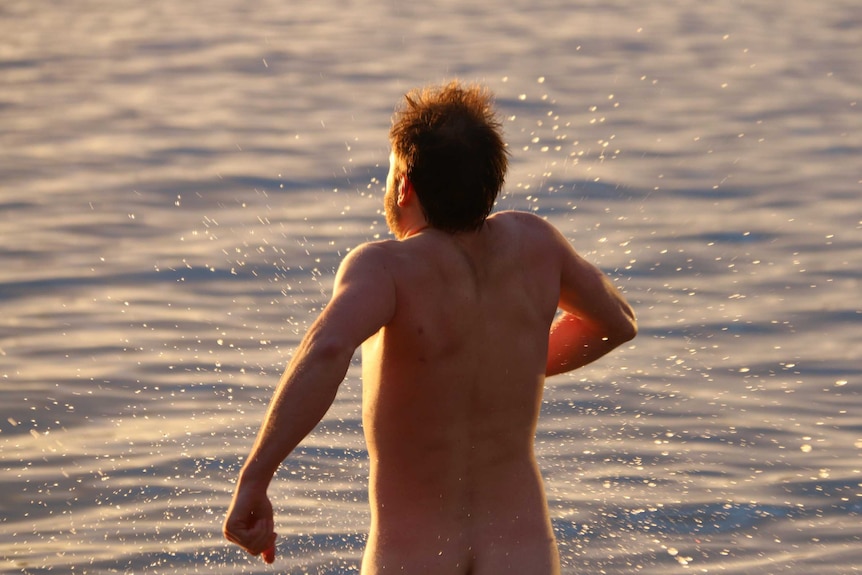 Male running into water at beach.