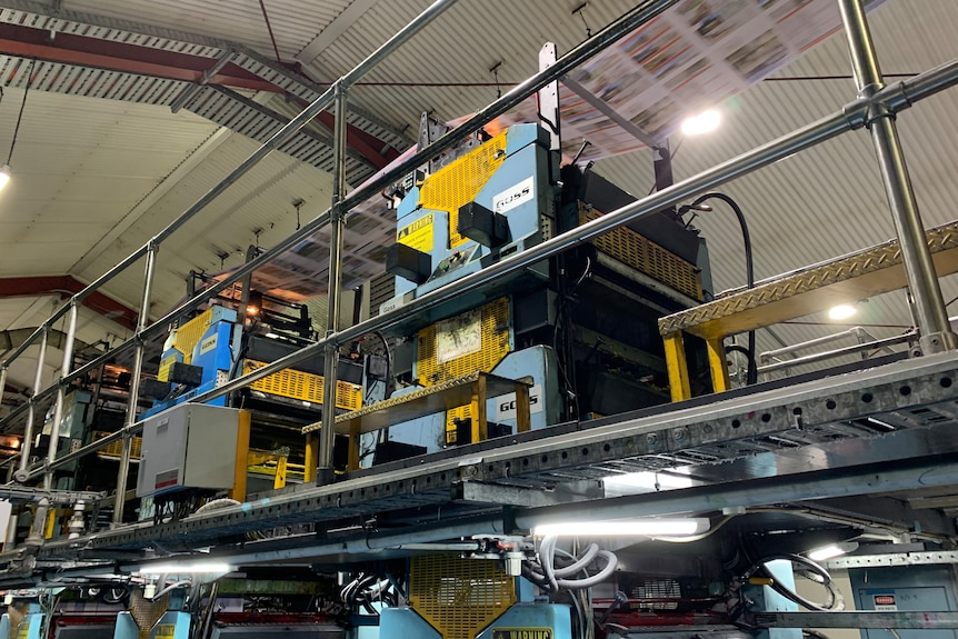 Papers run on a conveyor belt on a complicated machine in a warehouse 