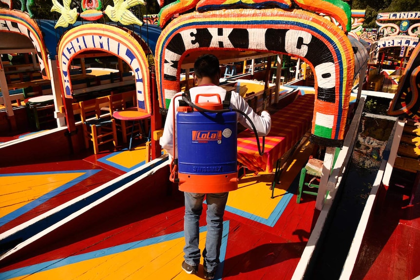 Álvaro Desiderio disinfects his boat in preparation for tourists for Day of the Dead in Xochimilco.