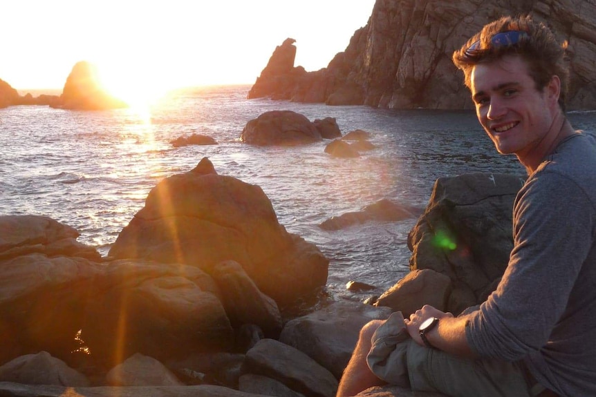 Picture of Jayden Whyte by the ocean at sunset.