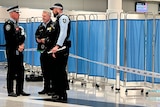 Police standing beside a blue barrier screen. 