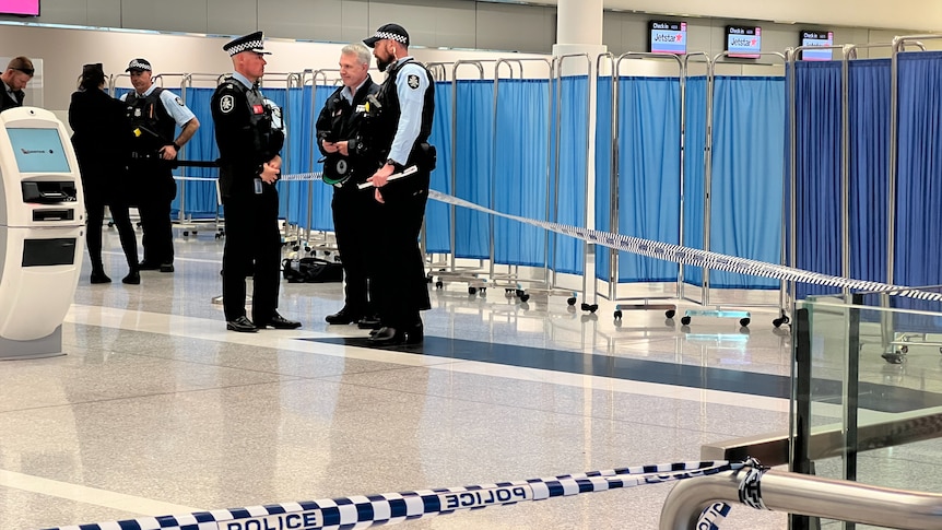 Police standing beside a blue barrier screen. 