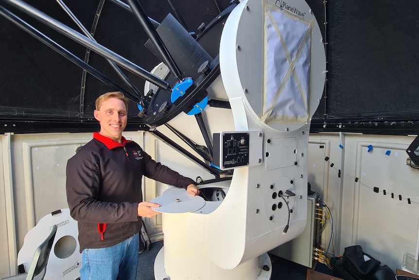 Man standing next to the base of a telescope