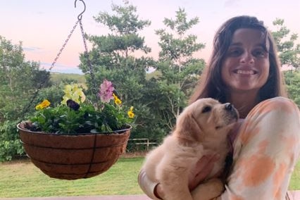 A young woman holds a puppy.