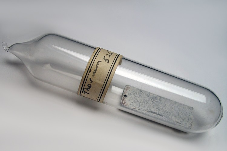 A glass bottle with a thin sheet of metal inside and a handwritten label stating 