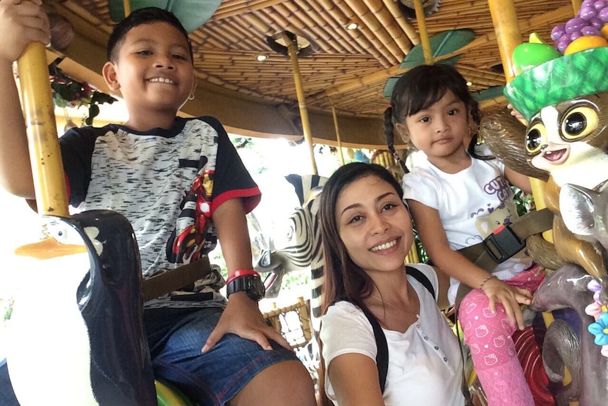 A woman, a boy and a girl posing smiling to camera.