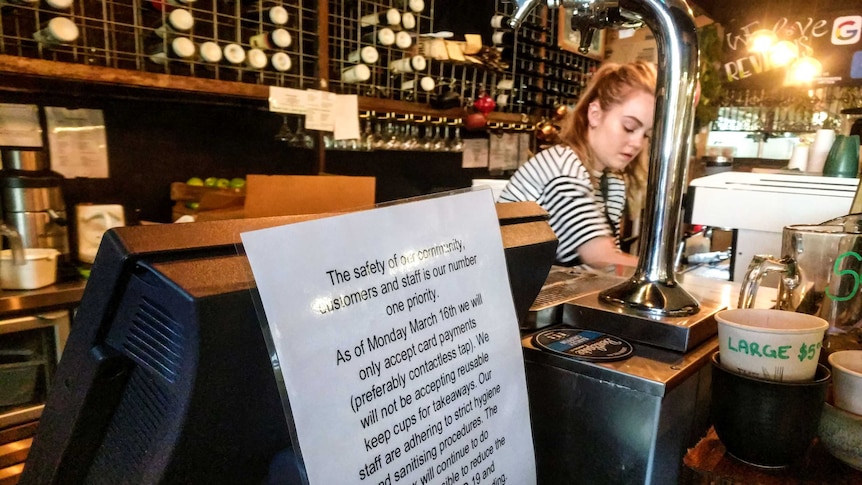 A sign at a cafe register says no cash payments will be accepted.