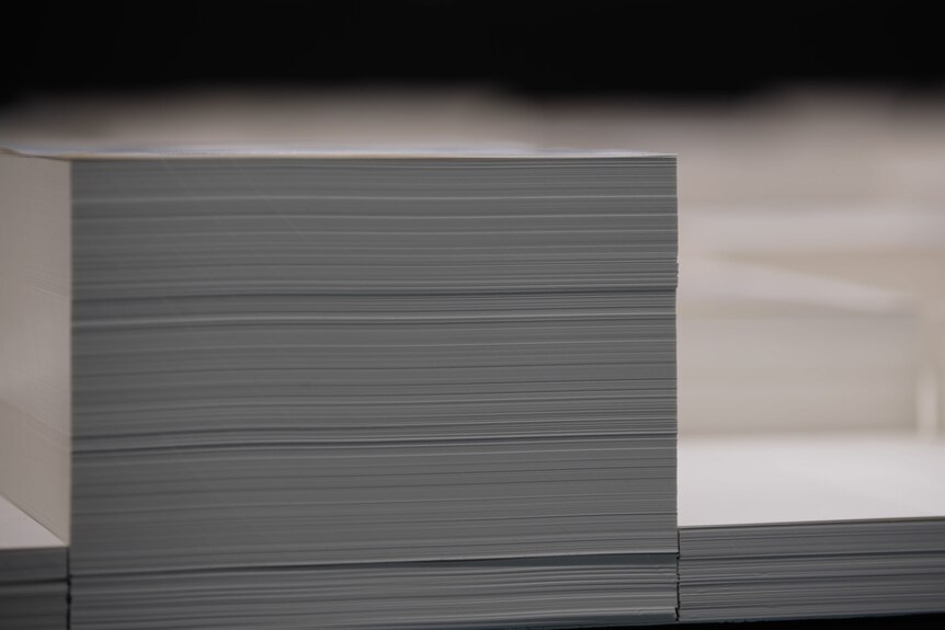 A close-up image shows stacks of blank A4 pages of differing heights.