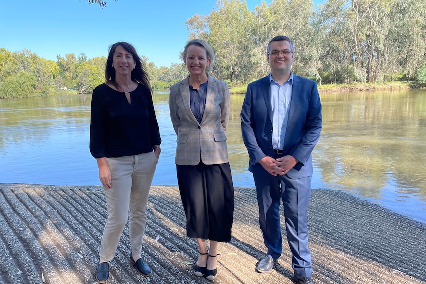 three people stand next to each other by the murray river