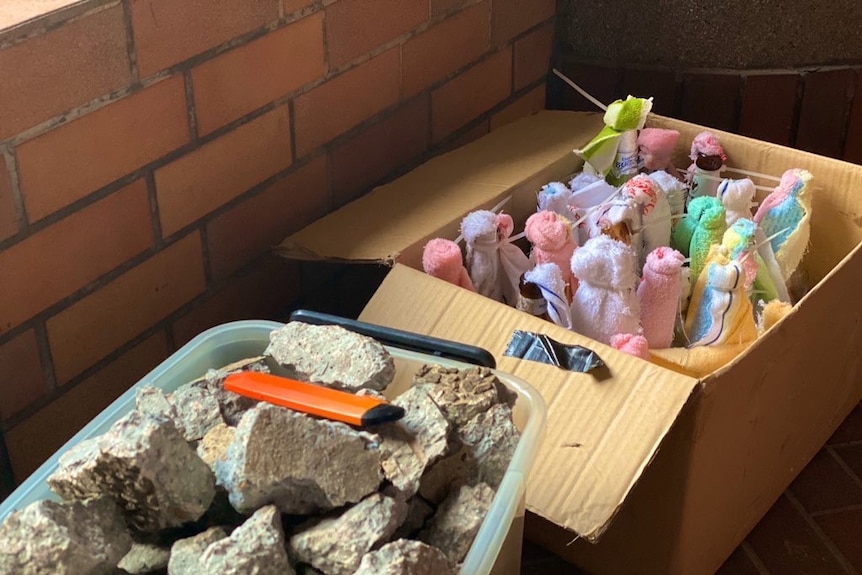A box of prepared molotov cocktails sits next to a box of rocks