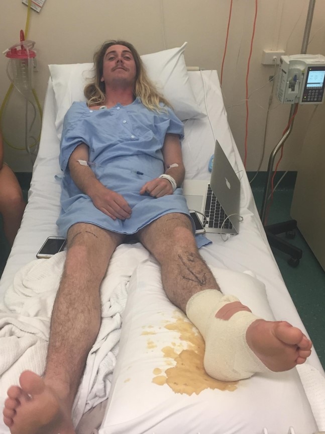 Bodyboarder Noah Symmans lies in a hospital bed with his foot bandaged after a shark attack in WA.