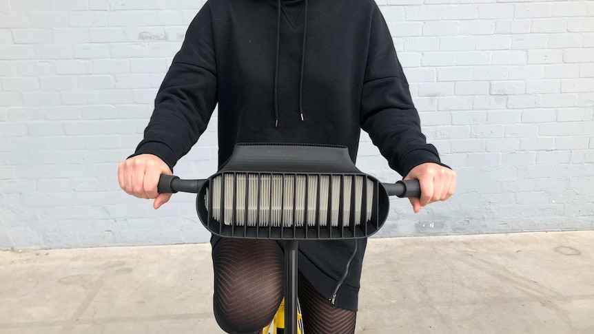 A shot of a  person's midsection, sitting astride a bicycle that is fitted with a large vent-like attachment.