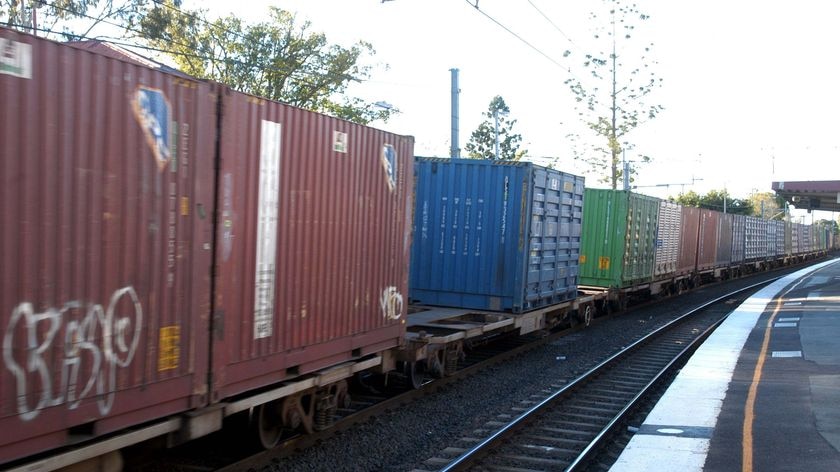 A freight train passes through a suburban railway station