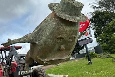 A large fibre glass potato wearing a hat lies at an angle on the ground