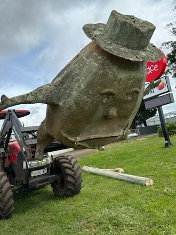 A large fibre glass potato wearing a hat lies at an angle on the ground