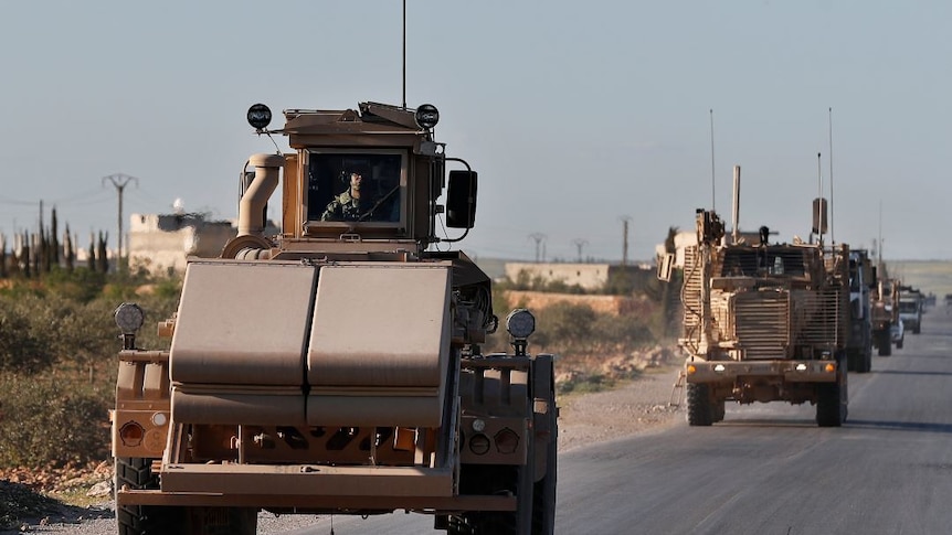 US troops ride in armoured vehicles in a convoy.