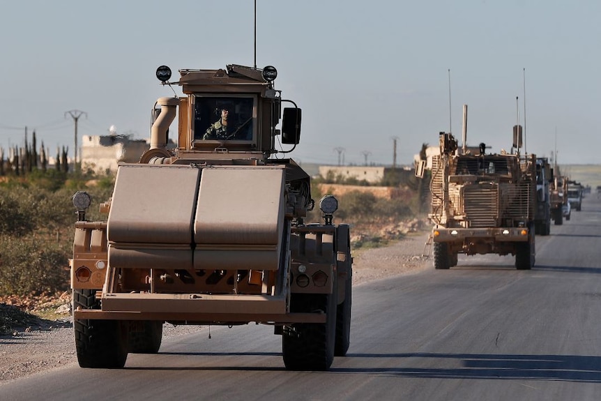 US troops ride in armoured vehicles in a convoy.
