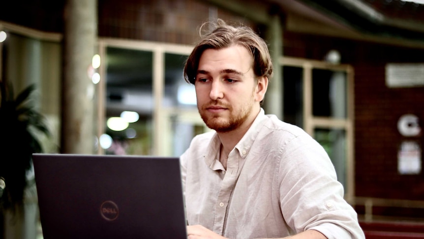 A young man looks at a Dell laptop