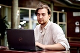 A young man looks at a Dell laptop