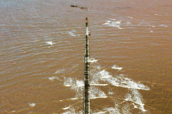 An aerial image of the severely damaged One Mile Jetty surrounded by muddy water