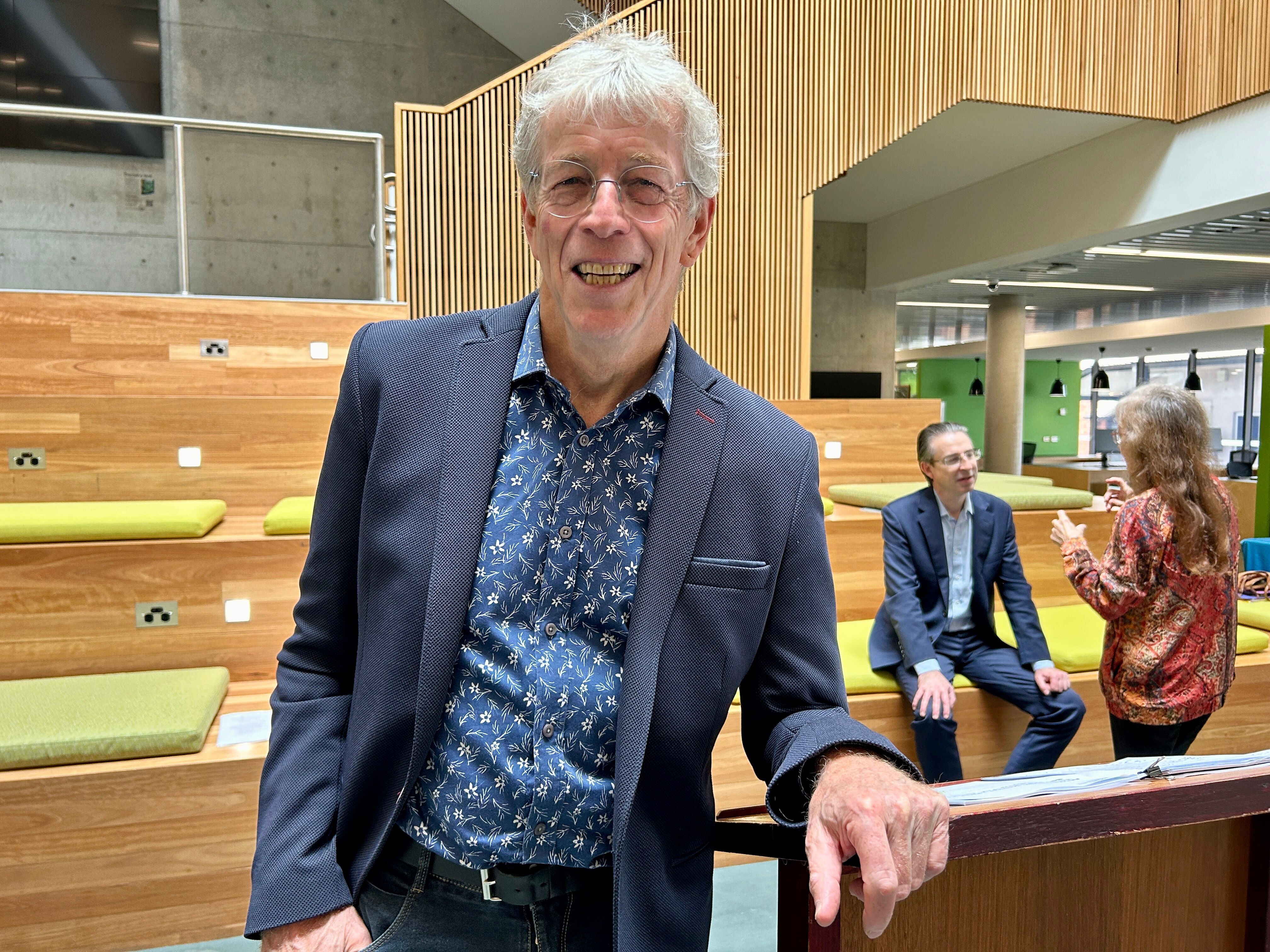 man in lofty space with two people behind him