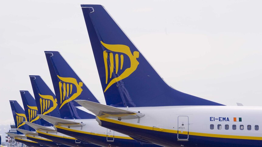 Five plane tails, each branded with a yellow Ryanair logo on a dark blue background.