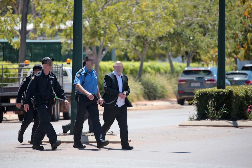 Police officers escort Francis John Wark through the WA town of Moora.