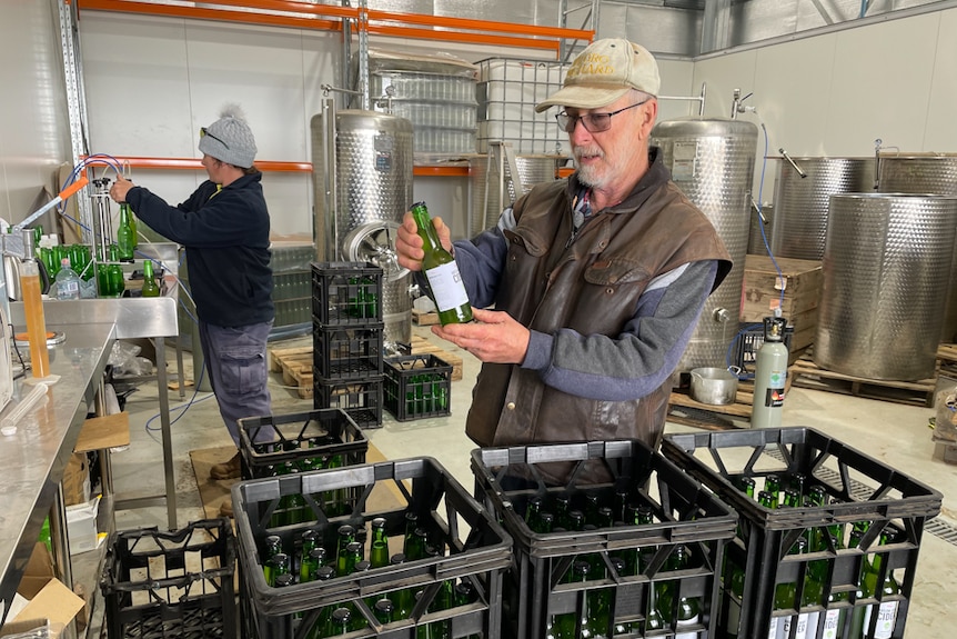 Ralph Wilson holding bottle inside apple cidery.