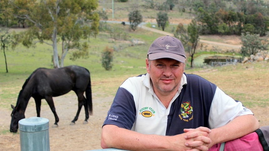 Peter Evans leans against the fence to the horse paddock.