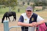 Peter Evans leans against the fence to the horse paddock.