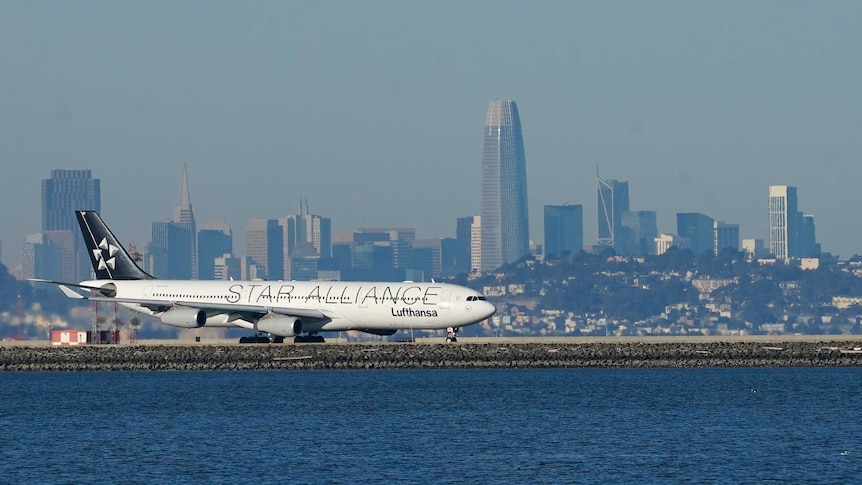 A passenger plane is seen sitting on a runway near a large body of water.