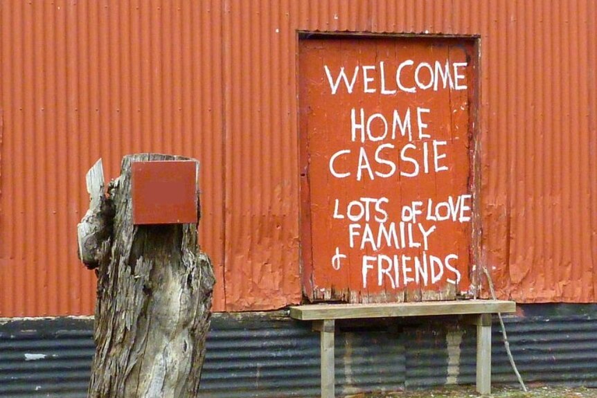 An orange tin wall with the words 'Welcome home Cassie' written on it