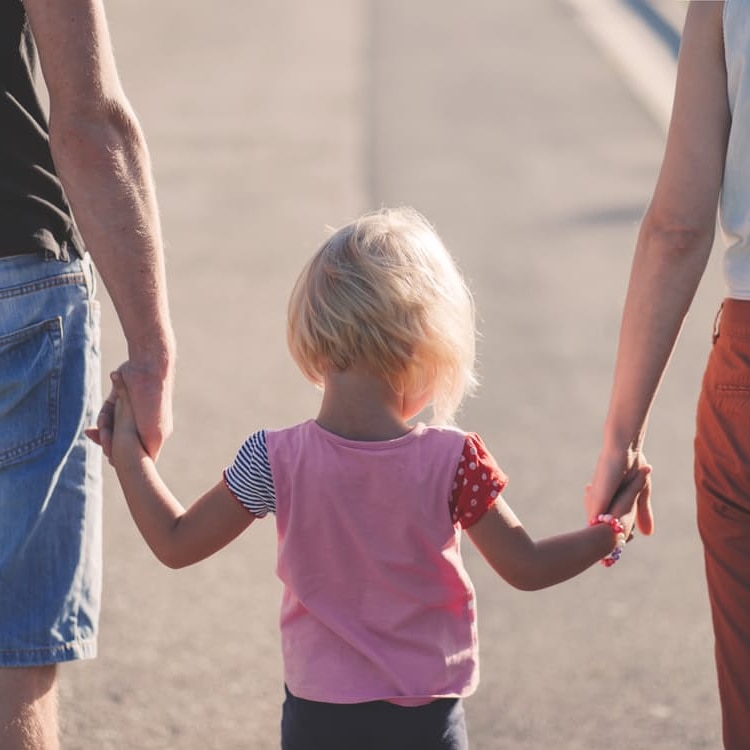 Child holds hands of mum and dad