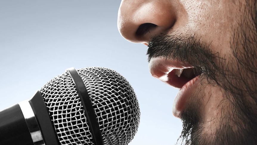 A close-up of a bearded man speaking into a microphone