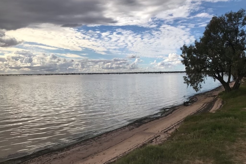 A lake at sunset with trees in the foreground