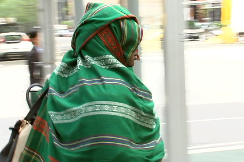 Rosa Riak leaves the County Court in Melbourne with a garment covering most of her face.