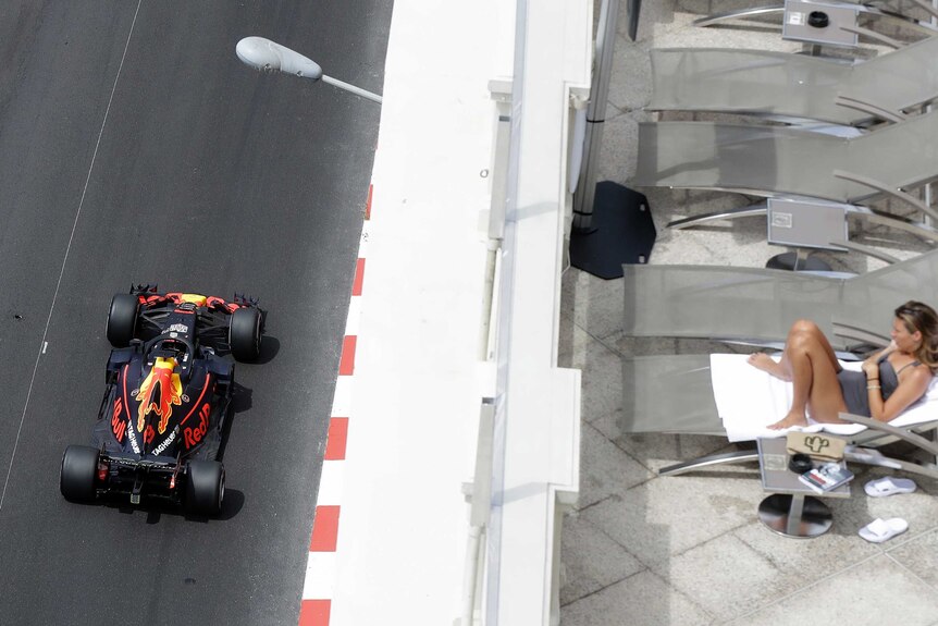 Daniel Ricciardo drives past as a woman sunbathes in Monaco