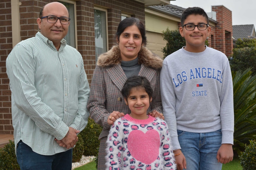 Rishi Prabhakar lives with his wife Aanchal and children Myra, 6, and Akul, 11, in Tarneit. They smile outside a brick house.