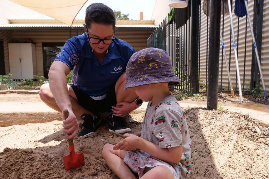 a woman plays with a child in a sandpit 