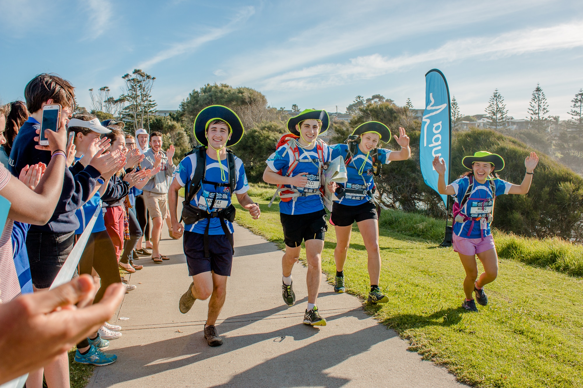 Four runners smile as they approach the finish line of a race