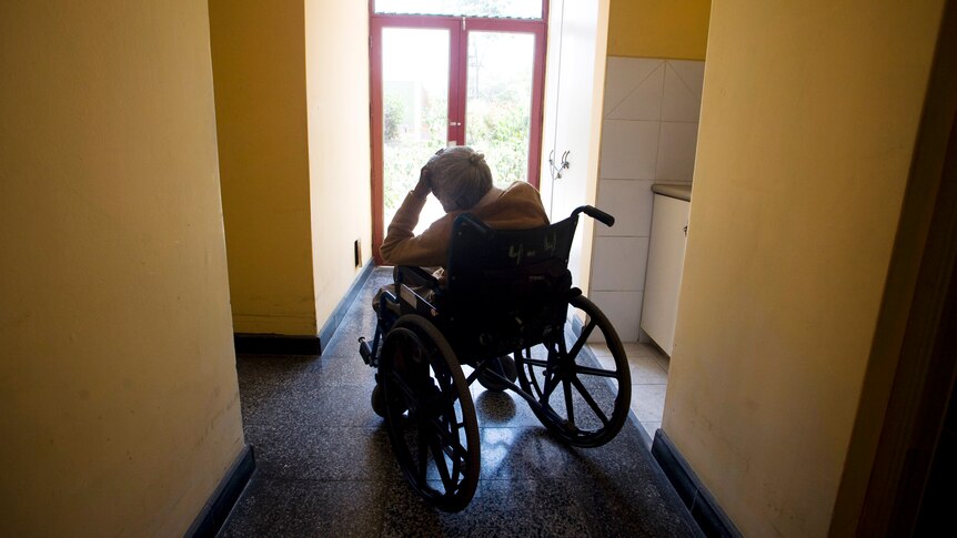 An elderly women rests on her wheel chair.