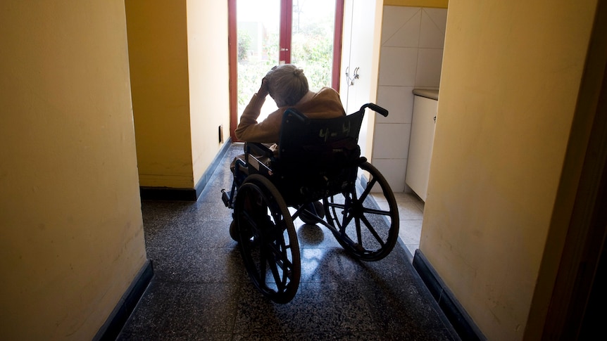 An elderley woman in a wheelchair in a house.
