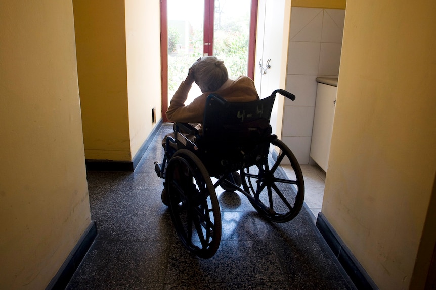 Elderly woman in a wheelchair sitting in a doorway 