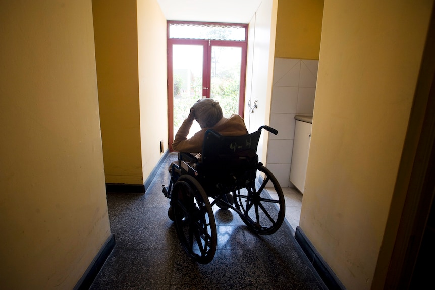 An elderly women rests on her wheel chair.