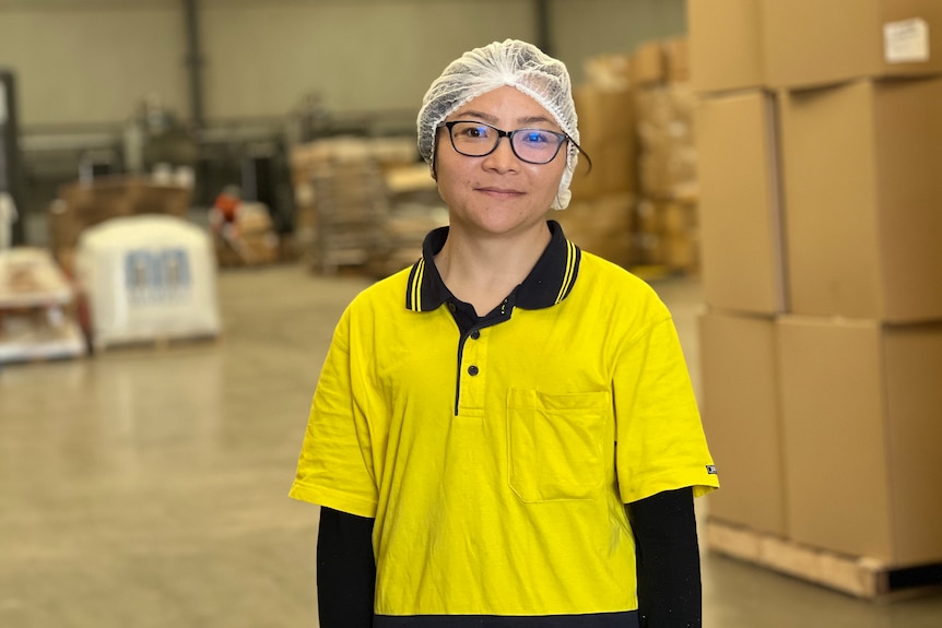 Female worker and Afghan refugee pictured in yellow T-shirt and hair cover at her work place.