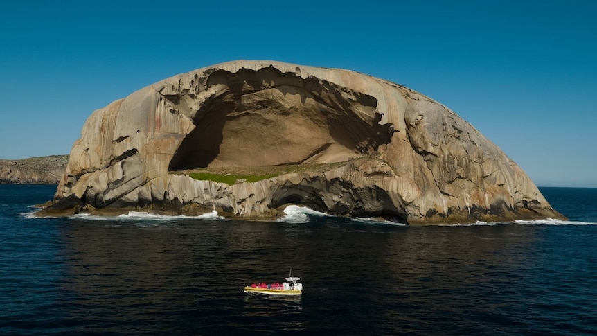 a large rock island with a small boat next to it.